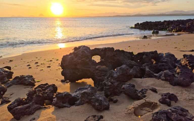 Durante o pôr do sol, paisagem de praia com pedras e sol refletido no mar