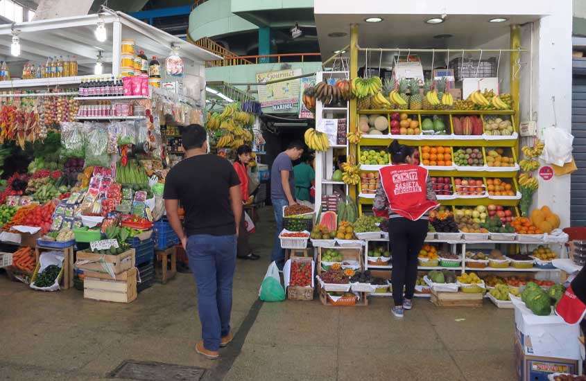 Mercado de frutas com pessoas comprando e vendedores, opção de turismo em lima