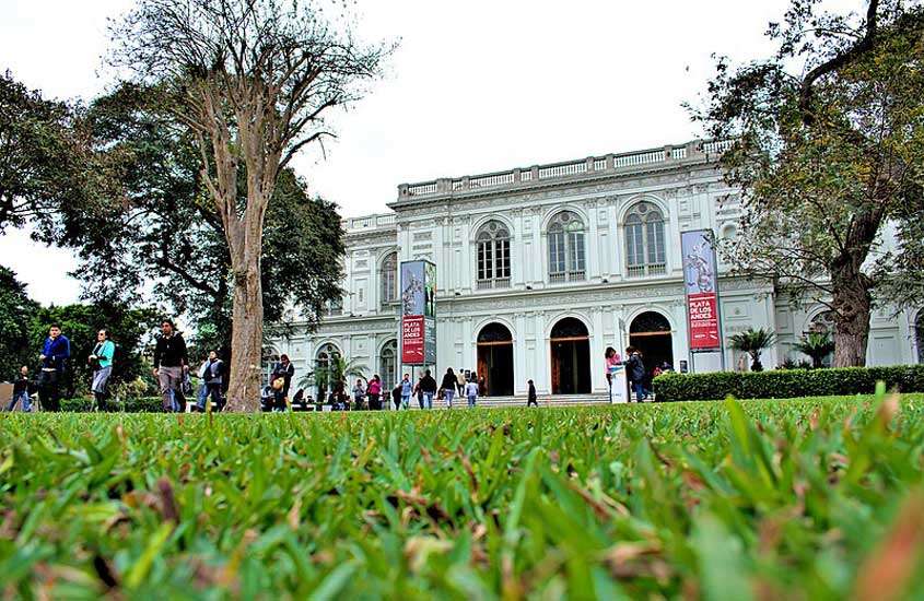 Em um dia nublado, fachada de um museu com árvores e parte gramada na frente, uma das opções de o que fazer em lima