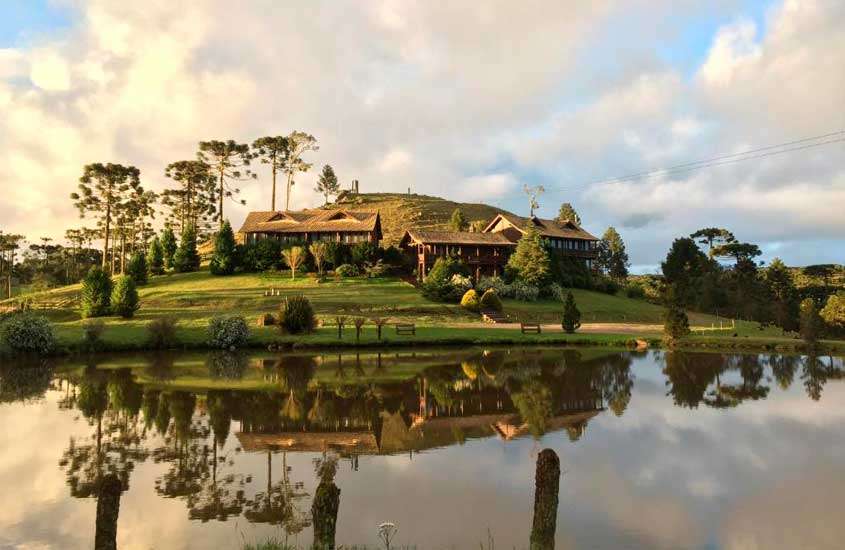 Durante um final de tarde lago de hotel fazenda na serra gaúcha com lago na frente, bancos, árvores e parte gramada