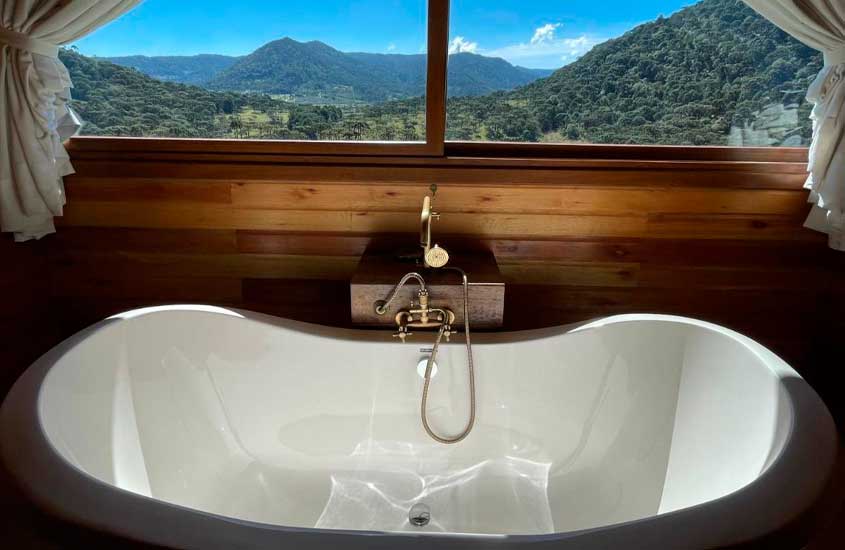 Área de banheira de um dos hotéis fazenda em santa catarina com vista para as montanhas e paredes de madeira
