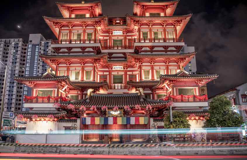 Fachada de um templo em Singapura iluminado com árvores na frente