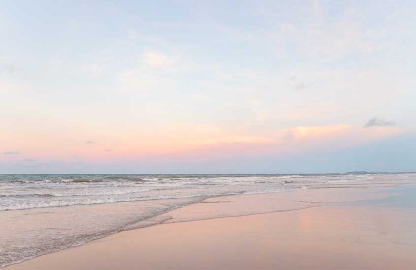 Por do sol de Aquiraz, um dos lugares onde ir no feriado de corpus christi com céu refletido no mar e na areia