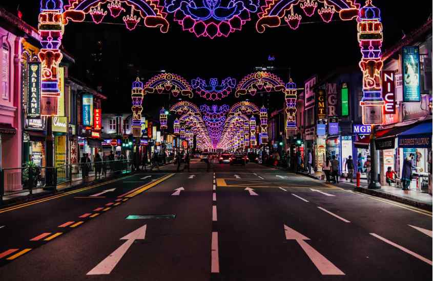 Durante a noite rua iluminada com lojas coloridas e pessoas ao redor