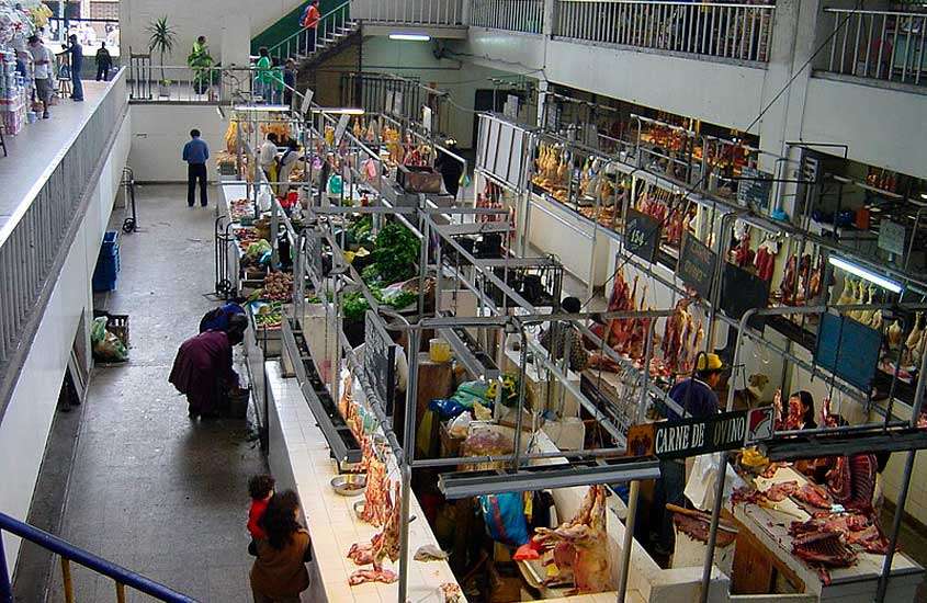 Interior de mercado central, com pessoas, alimentos e tendas