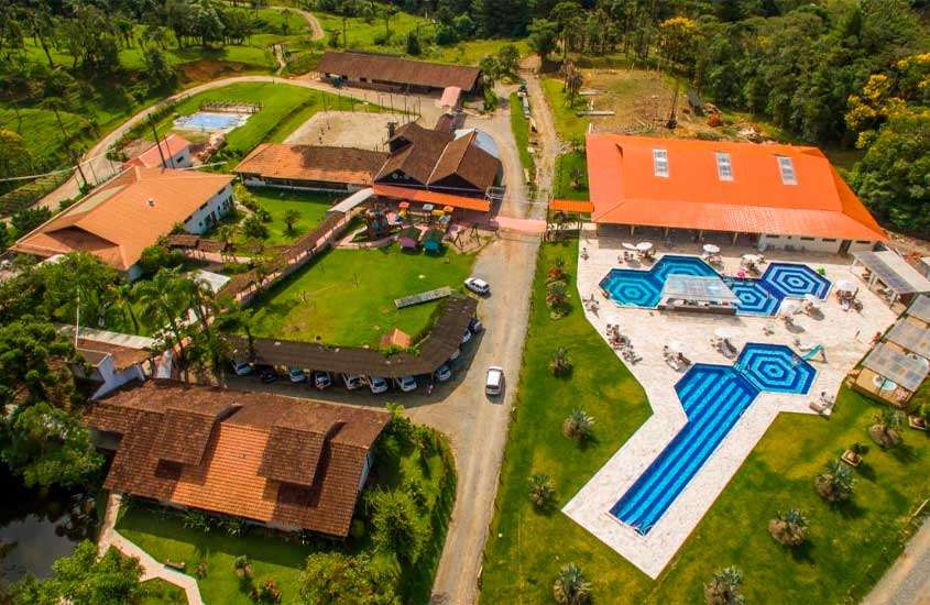 Vista aérea de um hotel fazenda em santa catarina com piscinas, carros e árvores ao redor