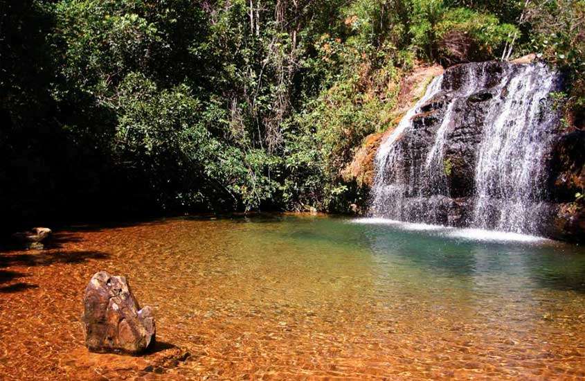 Em um dia de sol, cachoeira de Caldas Novas, um dos lugares para viajar no feriado de corpus christi com árvores ao redor e pedra no meio
