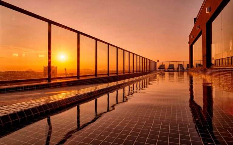 Durante o por do sol, cobertura de hotel perto do sambódromo rio de janeiro com piscina, espreguiçadeiras e paisagem da cidade