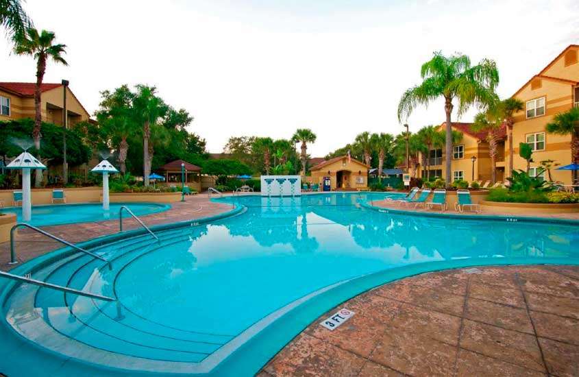 Em um dia nublado, área de lazer de um dos hotéis baratos em Orlando perto da disney com piscinas, cascatas, espreguiçadeiras, árvores ao redor