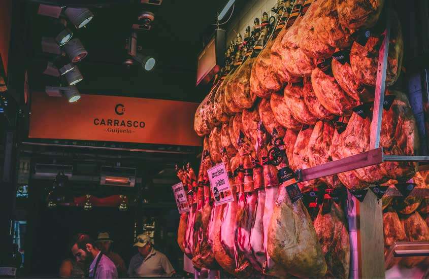 Interior de um frigorífico da cidade de madrid com carnes penduradas e pessoas ao redor