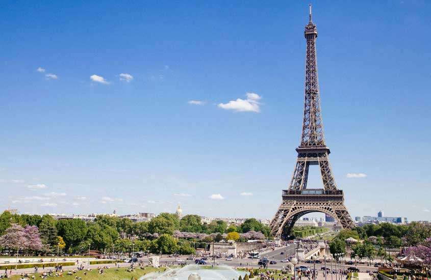 Em um dia de sol, paisagem de Torre Eiffel com árvores ao redor, símbolo da cultura na frança