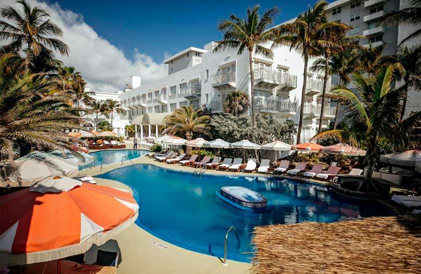 Em um dia e sol, área de lazer de um dos melhores hotéis em Miami Beach com piscinas, espreguiçadeiras, guarda-sóis e árvores ao redor