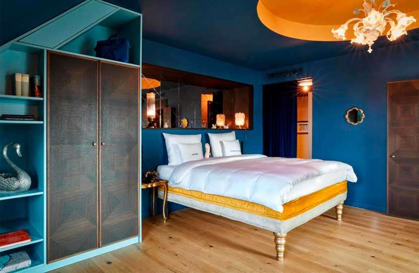 Quarto de hotel com cama de casa, armário de madeira, luminárias amarelas e peças decorativas
