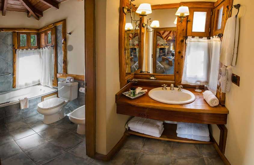 Banheiro de hotel com banheira, janelas pequenas, pia, toalhas e espelho