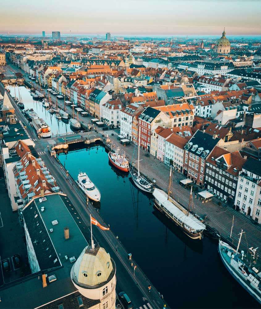 Durante o final da tarde, vista aérea da cidade de compenhague com canal no meio, barcos e casas coloridas
