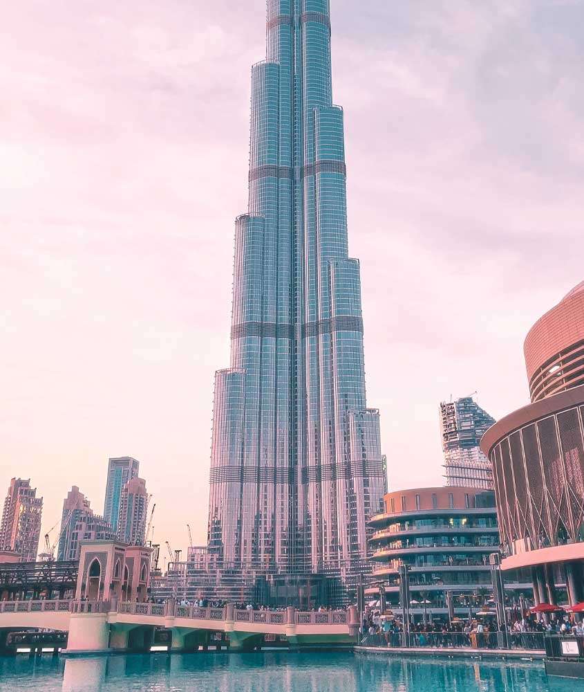 Em um final de tarde, vista do Burj Khalifa com prédios e mar ao redor