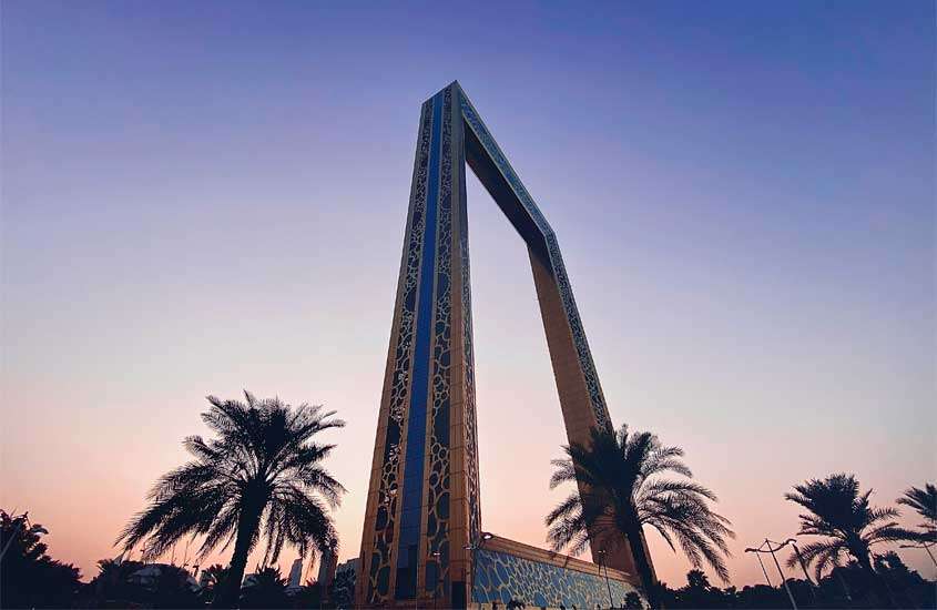 Durante o entardecer, monumento da cidade de Dubai com árvores ao redor