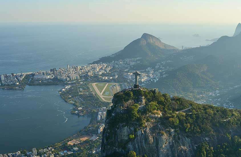 Em um dia de sol, vista aérea panorâmica da cidade do rio de Janeiro com montanhas, praia, Cristo Redentor no meio e cidade embaixo