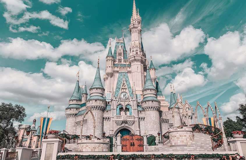 Em um dia de sol com nuvens, castelo da Disney com árvores ao redor