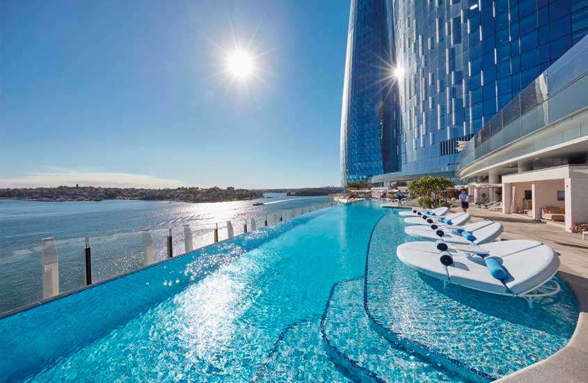 Em um dia ensolarado, área de lazer de um dos hotéis em Sydney com piscina grande paisagem promar, espreguiçadeiras e árvores