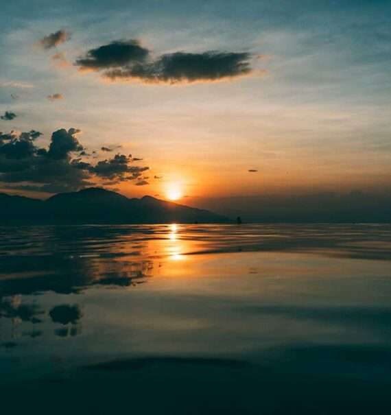 Durante o pôr do sol, vista do mar com reflexo do sol e céu com nuvens