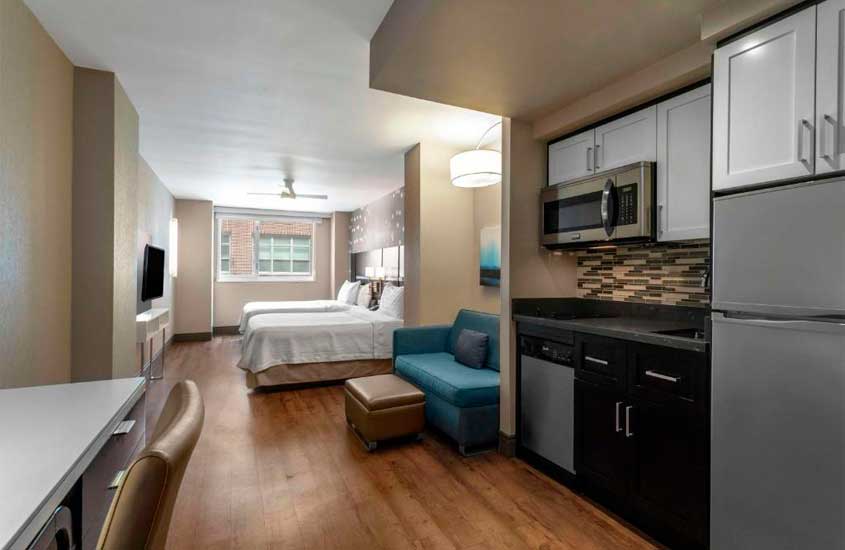 Quarto de um dos hotéis perto da Times Square com camas, poltrona, TV, mesa de trabalho e cozinha compacta