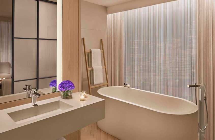 Banheiro de hotel perto da Times Square com banheira, flores decorativas, toalhas e cortinas