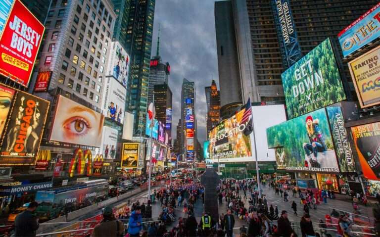 Em uma noite nublada, Times Square com painéis luminosos e pesosas ao redor