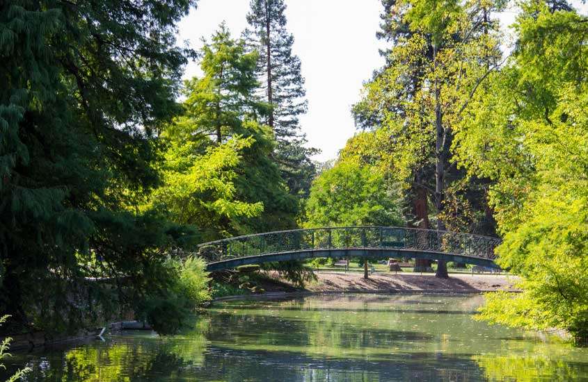 Em um dia ensolarado, parque com ponte, rio e árvores ao redor, uma das opções do que fazer em bordeaux