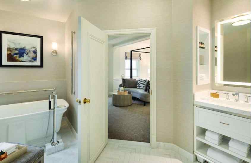 Banheiro de hotel onde ficar em quebec com banhiera, toalhas, espelho e quarto no fundo