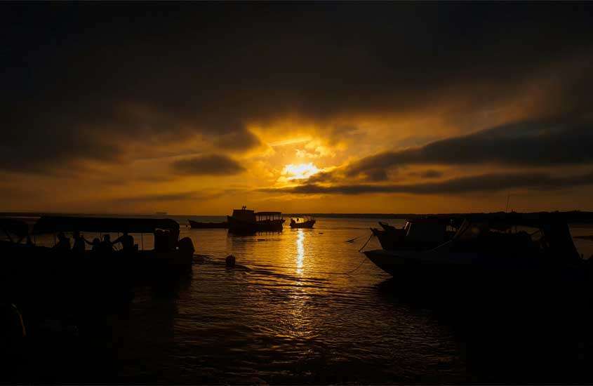 Durante o pôr do sol, na ilha do mel uma das cidades para passar o réveillon com barcos aportados na beira do mar