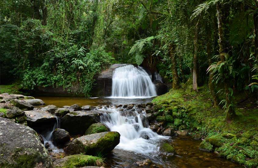Em um dia nublado, cachoeira de Visconde de Maua, uma das cidades para passar o réveillon, com plantas, pedras e árvores ao redor