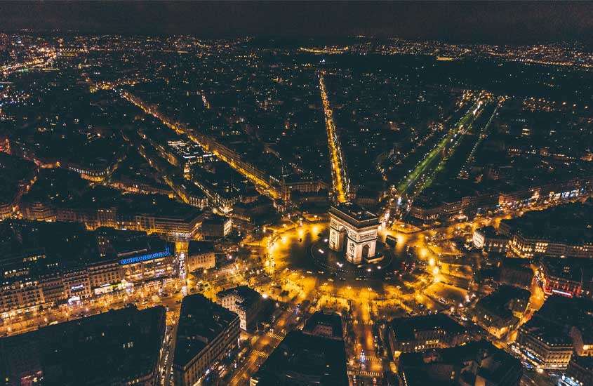 Durante a noite, vista aérea do arco do triunfo em paris iluminado por luzes amarelas ao redor