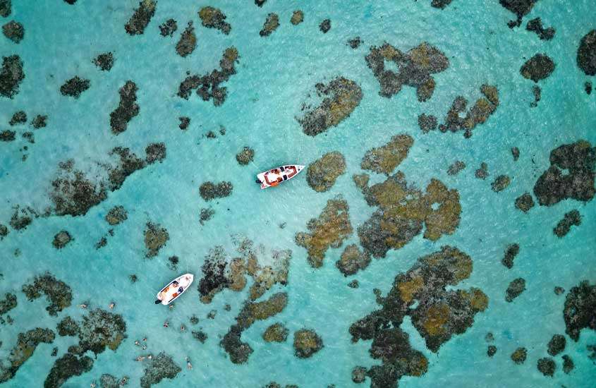 Vista aérea depraia em São miguel do Gostoso, um dos lugares para passar o réveillon, com corais, água cristalina e barcos
