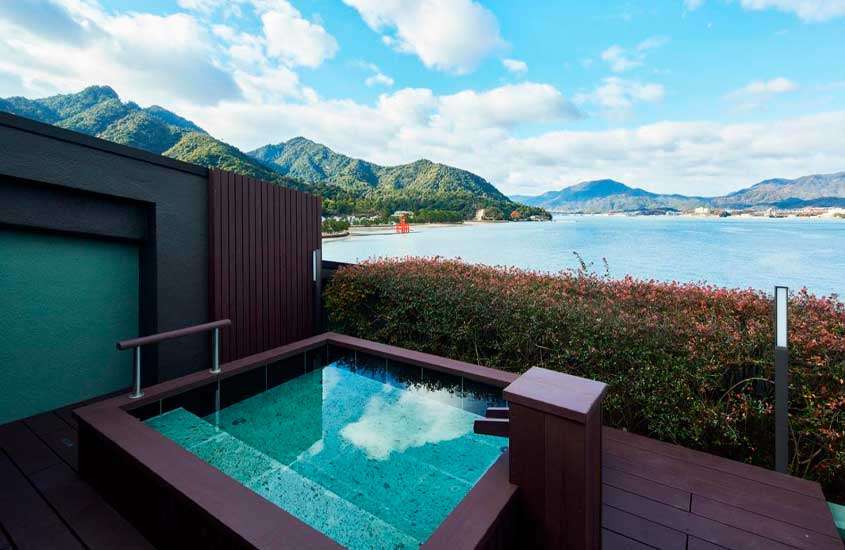 Em um dia de sol, banheira de um hotel miyajima com paisagem do mar e dar montanhas