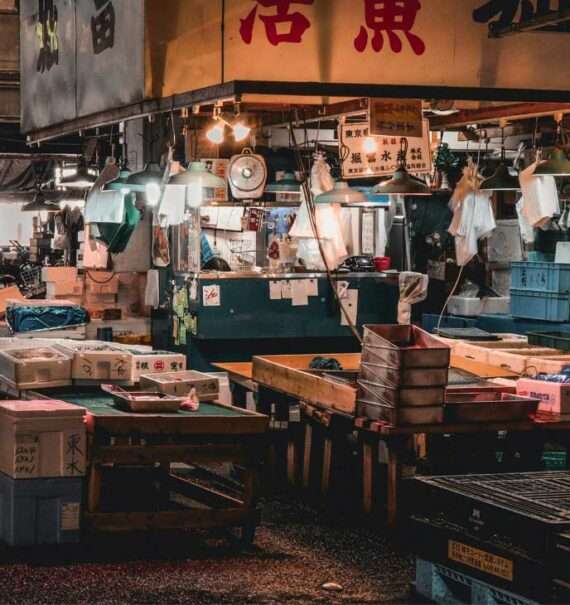 Loja do Tsukiji Fish Market com pessoas ao redore luzes amarelas
