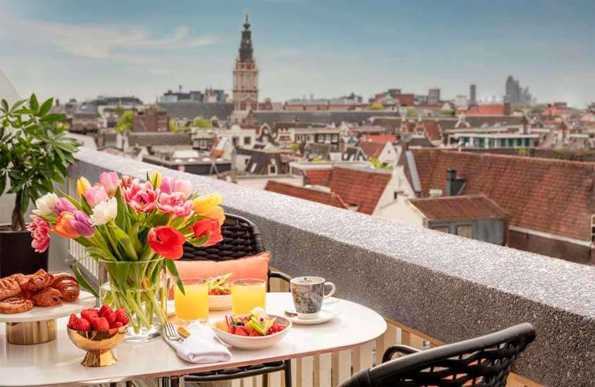 Terraço de hotel em amsterdã com mesa, cadeiras, café da manhã servido, plantas decorativas e paisagem da cidade