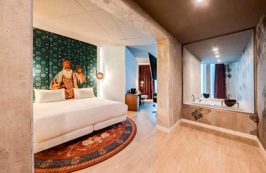 Quarto de hotel em amsterdam com cama de casal, banheira de hidromassagem, TV, tapete e mural