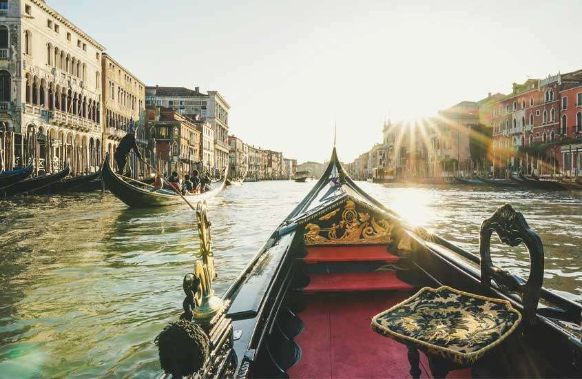 Em um dia de sol, paisagem de um canal durante um passeio de gôndola, uma das opções do que fazer em Veneza com outros barcos ao redor