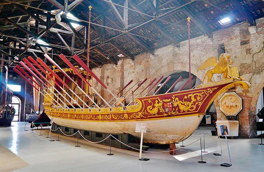 Interior de um museu com barcos de madeira e outras obras