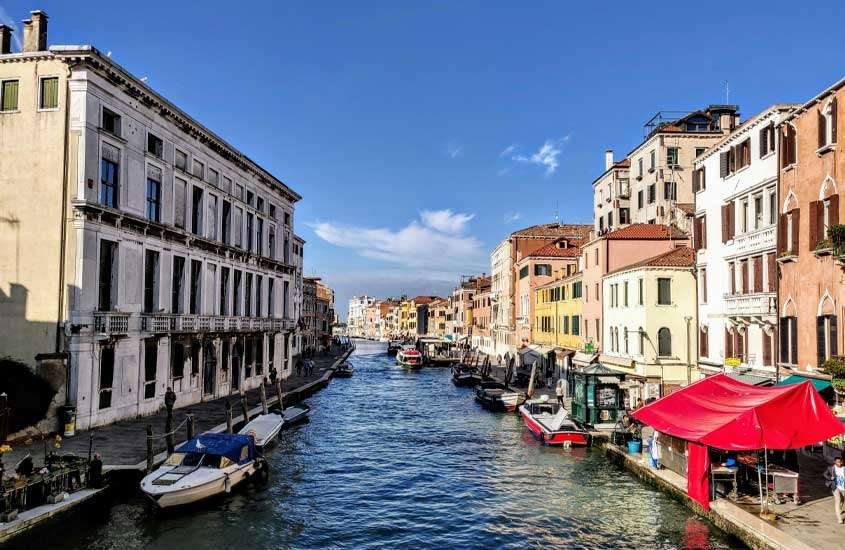 Em um dia de sol, canal da cidade de Veneza com barcos aportados