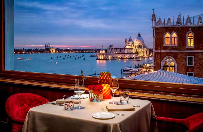 Durante o anoitecer, varanda com mesa de jantar posta e vista para curtir a cidade, uma das alternativas de o que fazer em Veneza