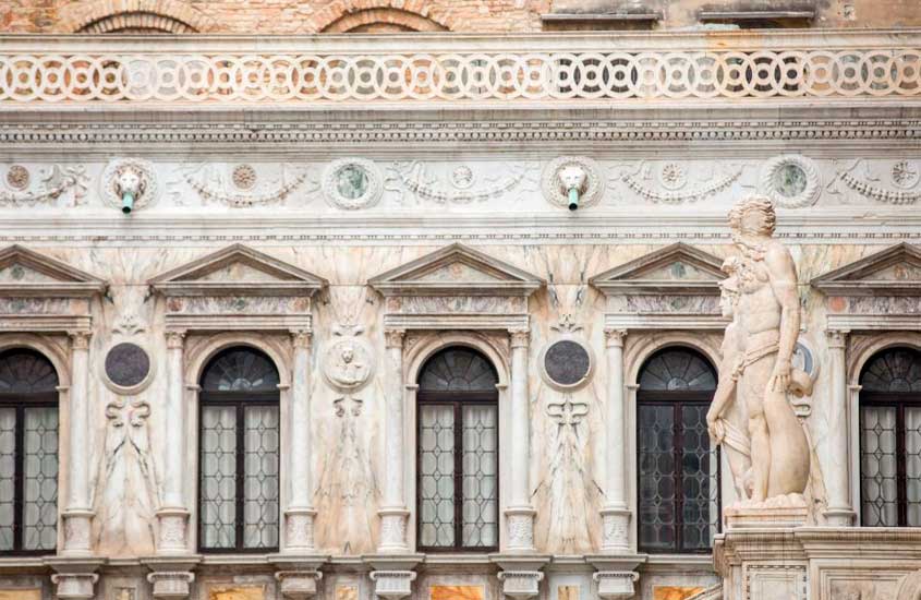 Fachada de um prédio damoso com escultura na porta e ornamentação em mármore