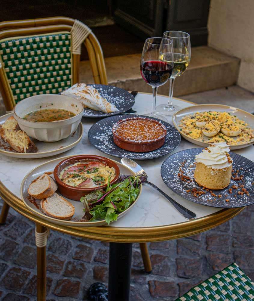 Mesa posta com sopa, sobremesas, assado e vinhos e cadeiras ao redor
