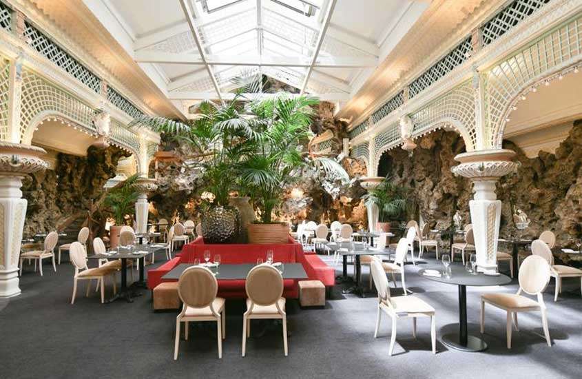 Interior de um dos restaurantes em Bordeaux com mesas, cadeiras, plantas e flores ao redor