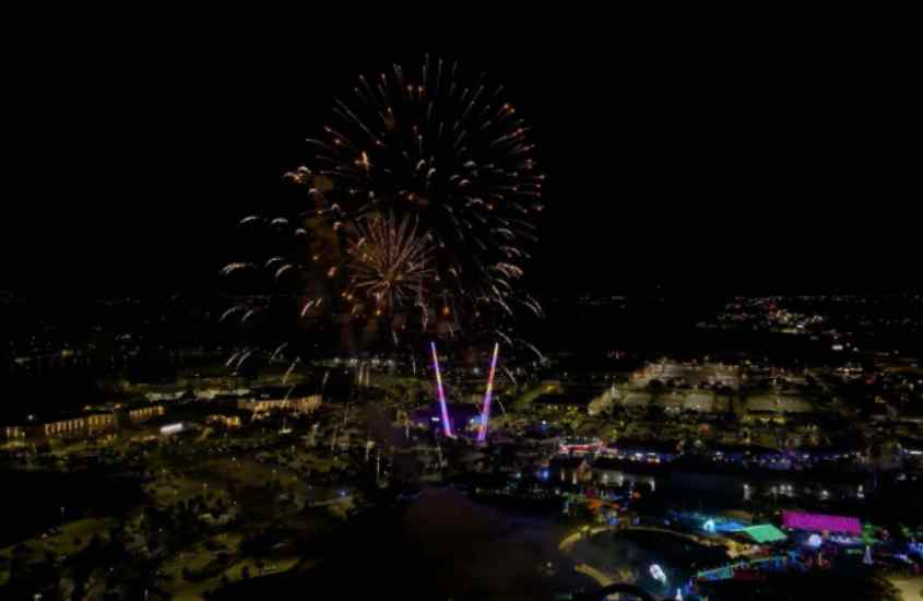 Durante a noite de Réveillon em Orlando, visão da queima de fogos e da cidade iluminada por luzes coloridas