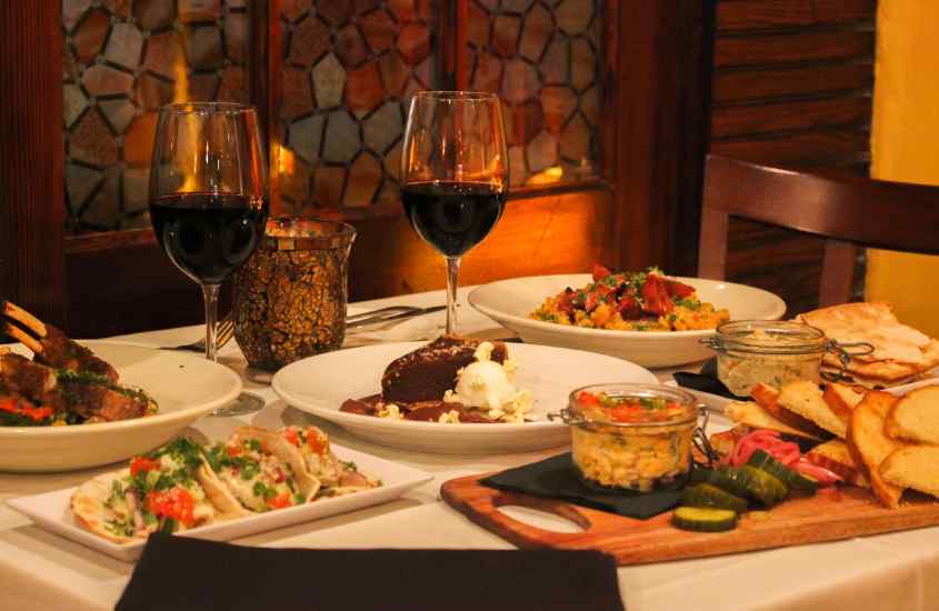 Mesa posta com comidas diversas e taças de vinho com vela decorativa