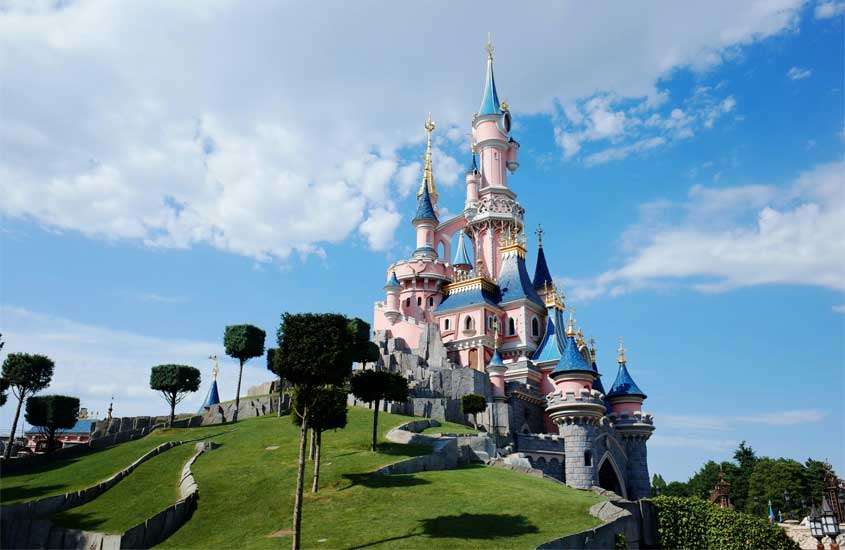 Em um dia de sol, Disneyland Paris com árvores ao redor, um dos lugares legais para passar o Réveillon em Paris