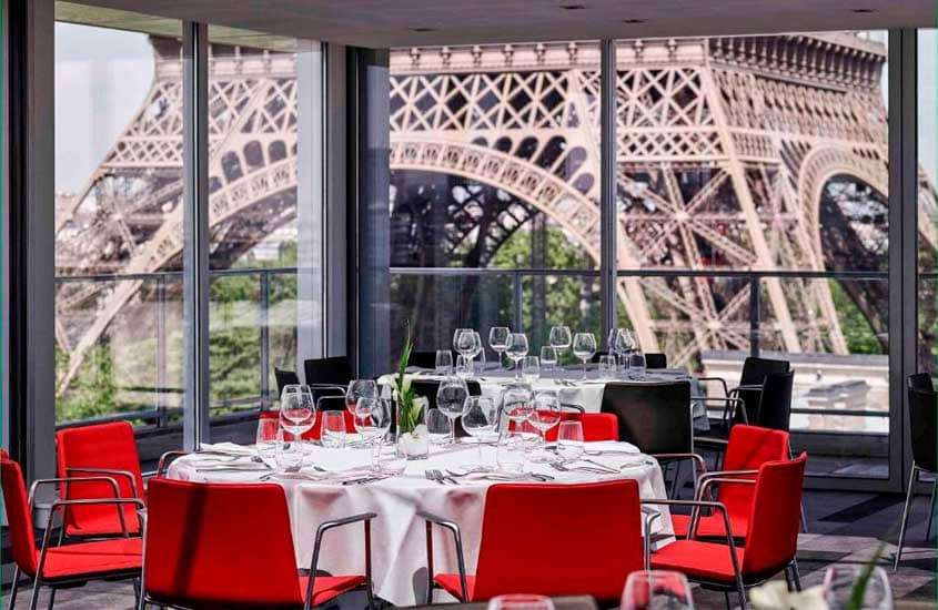 Um restaurante de frente a torre Eiffel para passar o ano novo em Paris com mesas postas e janelas grandes
