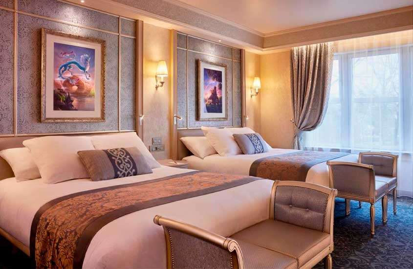 Um hotel para passar o ano novo em Paris com camas de casal, quadros decorativos, janelas grandes acortinadas e sofás na frente